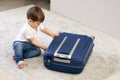 Cute little baby boy closing blue suitcase finished packing for vacation.