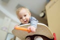 Cute little baby boy eating carrot sitting in a white highchair. Introducing first solid foods. Fresh vegetables for infants. Royalty Free Stock Photo