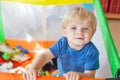 Cute little baby boy playing in colorful playpen, indoors Royalty Free Stock Photo