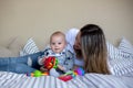 Cute little baby boy, playing with his mom at home in bed with lots of colorful toys Royalty Free Stock Photo