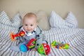 Cute little baby boy, playing at home in bed with lots of colorful toys Royalty Free Stock Photo