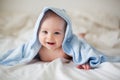 Cute little baby boy, relaxing in bed after bath, smiling happily Royalty Free Stock Photo