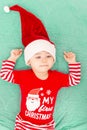 Cute little baby boy with Santa hat on his first Christmas. Adorable toddler child lying on green coverlet. Christmas Royalty Free Stock Photo