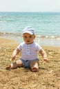 Cute little baby boy sitting on the sand beach near by blue sea Royalty Free Stock Photo