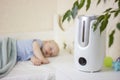 Cute little baby boy sleeping in bedroom with air humidifier. Royalty Free Stock Photo