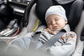 Cute little baby boy sleeping strapped into infant car seat in passenger compartment during car drive. Royalty Free Stock Photo