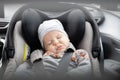 Cute little baby boy sleeping strapped into infant car seat in passenger compartment during car drive. Royalty Free Stock Photo