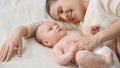 Cute little baby boy and smiling mom lying on bed in bedroom Royalty Free Stock Photo