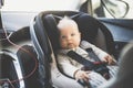 Cute little baby boy strapped into infant car seat in passenger compartment during car drive. Royalty Free Stock Photo