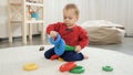 Cute little baby boy trying assembling colorful toy pyramid tower. Baby development, child playing games, education and learning Royalty Free Stock Photo