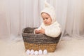 Cute little baby in bunny costume sitting in the basket and holding an easter egg Royalty Free Stock Photo