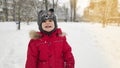 Cute little baby child boy in red sport jaket having fun playing on playground, city park outdoors during snowfall in winter. Royalty Free Stock Photo