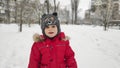 Cute little baby child boy in red sport jaket having fun playing on playground, city park outdoors during snowfall in winter. Royalty Free Stock Photo