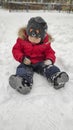 Cute little baby child boy in red sport jaket having fun playing on playground, city park outdoors during snowfall in winter. Royalty Free Stock Photo