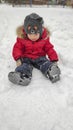 Cute little baby child boy in red sport jaket having fun playing on playground, city park outdoors during snowfall in winter. Royalty Free Stock Photo