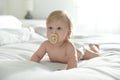 Cute little baby in diaper with pacifier lying on bed at home Royalty Free Stock Photo