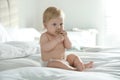 Cute little baby in diaper with pacifier sitting on bed at home Royalty Free Stock Photo