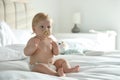 Cute little baby in diaper with pacifier sitting on bed at home. Space for text Royalty Free Stock Photo