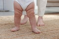 Cute little baby doing first steps with mother`s help at home, closeup Royalty Free Stock Photo