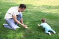 Cute little baby with father crawling on grass in park Royalty Free Stock Photo