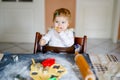 Cute little baby girl baking gingerbread Christmas cookies at home. Adorable blond happy healthy child having fun in Royalty Free Stock Photo