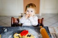 Cute little baby girl baking gingerbread Christmas cookies at home. Adorable blond happy healthy child having fun in Royalty Free Stock Photo