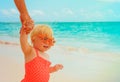 Cute little baby girl on beach holding mother hand, family at beach