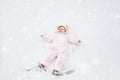 Cute little baby girl in colorful winter clothes making snow angel, laying down on snow. Active outdoors leisure with Royalty Free Stock Photo