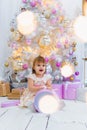 Cute little baby girl opening gift box with decorating christmas tree on background Royalty Free Stock Photo