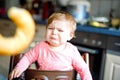 Cute little baby girl eating bread. Adorable child eating for the first time piece of pretzel or croissant. Healthy sad