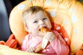 Cute little baby girl eating bread. Child eating for the first time piece of pretzel. First food after breastfeeding