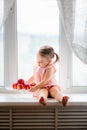 Cute little baby girl eats peaches on the window Royalty Free Stock Photo