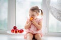 Cute little baby girl eats peaches on the window Royalty Free Stock Photo