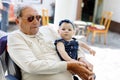 Cute little baby girl with grandfather on summer day in garden Royalty Free Stock Photo