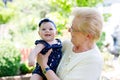 Cute little baby girl with grandmother on summer day in garden Royalty Free Stock Photo