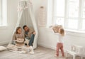 Cute baby girl with her parents play in a minimalistic children`s room.