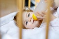 Cute little baby girl holding bottle with formula mild and drinking. Child in baby cot bed before sleeping Royalty Free Stock Photo