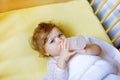 Cute little baby girl holding bottle with formula mild and drinking. Child in baby cot bed before sleeping Royalty Free Stock Photo