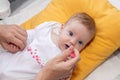 Cute little baby girl lying on the bed and eating rice soup with spoon. Mother feeding her baby girl. The baby girl is four months Royalty Free Stock Photo