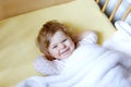 Cute little baby girl lying in cot before sleeping. Happy calm child in bed. Going sleep. Peaceful and smiling child