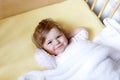 Cute little baby girl lying in cot before sleeping. Happy calm child in bed. Going sleep. Peaceful and smiling child