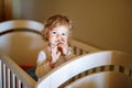 Cute Little Baby Girl Lying in Cot after Sleeping. Healthy Happy Child in Bed Climbing Out. Danger for Babies and Royalty Free Stock Photo