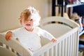 Cute Little Baby Girl Lying in Cot after Sleeping. Healthy Happy Child in Bed Climbing Out. Danger for Babies and Royalty Free Stock Photo