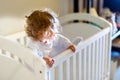 Cute little baby girl lying in cot after sleeping. Healthy happy child in bed climbing out. Royalty Free Stock Photo