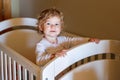 Cute Little Baby Girl Lying in Cot after Sleeping. Healthy Happy Child in Bed Climbing Out. Danger for Babies and Royalty Free Stock Photo