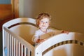 Cute Little Baby Girl Lying in Cot after Sleeping. Healthy Happy Child in Bed Climbing Out. Danger for Babies and Royalty Free Stock Photo