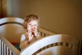 Cute Little Baby Girl Lying in Cot after Sleeping. Healthy Happy Child in Bed Climbing Out. Danger for Babies and Royalty Free Stock Photo