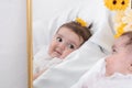 Cute little baby girl lying in her crib and looking in a mirror Royalty Free Stock Photo