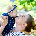 Cute little baby girl with mother on summer day in garden. Happy woman holding smiling child on arm. Kissing, hugging.. Royalty Free Stock Photo