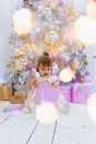 Cute little baby girl opening gift box with decorating christmas tree on background Royalty Free Stock Photo